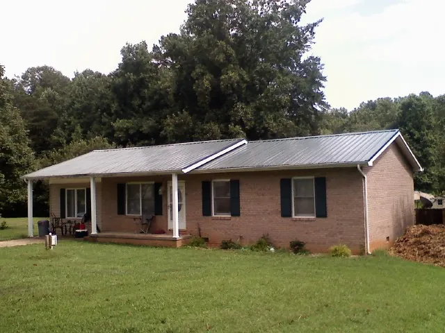 Gray metal roof on a brick ranch house with a side carport in Riverton